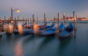 Scenic view of gondolas in motion on water waves and San Giorgio church as background in Venice, Italy