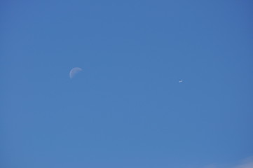 Moon and Distant Airplane with Blue Sky Background