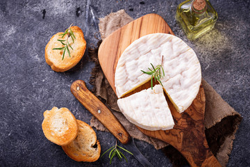 Camembert cheese with rosemary on wooden board