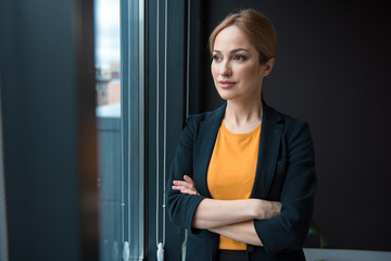 Portrait of smiling businesswoman locating in room. She watching at window. Relax concept