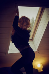 Young woman silhouette near window in dark bedroom