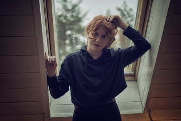 oung woman in black jacket with hood near window