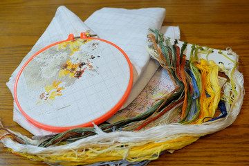 Cross stitch with colored threads on white fabric.