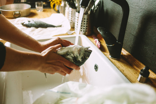 Cooking a fresh gilthead seabream with lemon, garlic and herbs, covered with salt