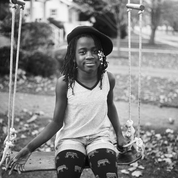 Stylish black girl with berret on a swing