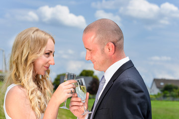 Glückliches und verliebtes junges Paar stößt mit einem Glas Sekt auf die gemeinsame Zukunft an
