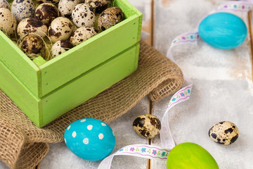 Multicolored Easter eggs in a wooden box, ribbons on a wooden background. Country style.