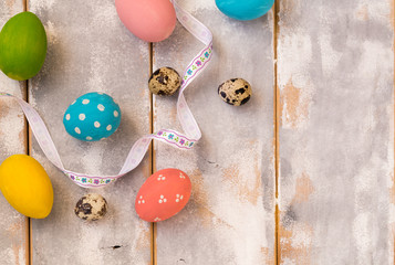 Multicolored Easter eggs and ribbons on a wooden background. Country style. Flat lay. Space for text