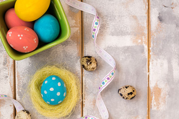 Multicolored Easter eggs in a wooden box and nest ,ribbons on a wooden background. Country style. Flat lay. Copy space