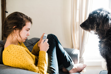 Teen on phone with dog who wants attention