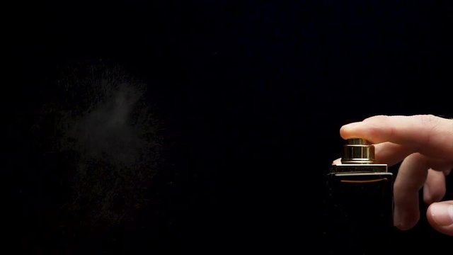 Close up of a spray bottle drops on black background. Male perfume bottle on a dark background. close up of a spray bottle drops on black background