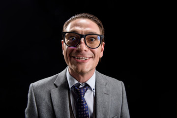 Joyful mood. Portrait of easygoing positive young businessman in suit is standing and looking at camera with wide smile. Isolated background