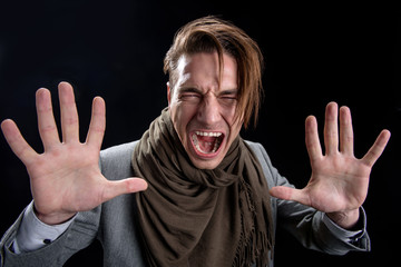 Portrait of crazy desperate man is standing and screaming loudly. He is looking at camera with...