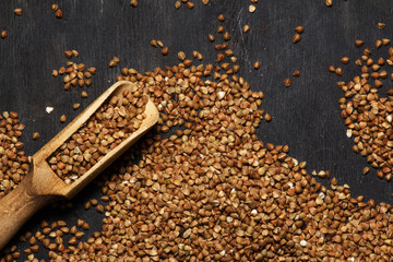 Buckwheat brown in a bowl on a black wooden background. Close-up. View from above.