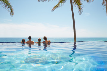 Family with two kids on edge of infinity pool overlooking ocean