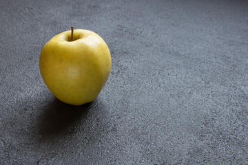 Ripe juicy apple on a dark concrete background.