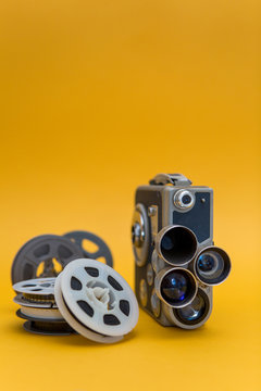 Vintage cinema camera and reels on yellow background