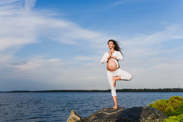 Yoga tree pose by pregnat woman.