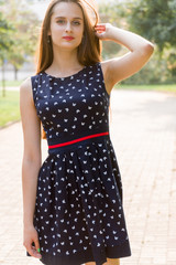 Young, beautiful, attractive woman in a stylish dress, posing on camera. She laughs, poses for the camera, her hair blowing in the wind, looking very happy