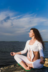 Fototapeta na wymiar Meditating pregnant woman in lotus position.