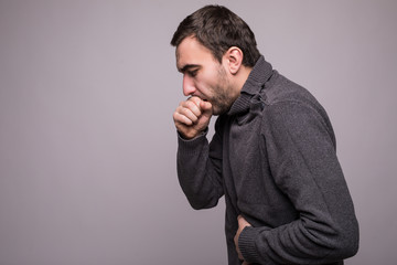 Handsome man with beard coughing a lot on grey background
