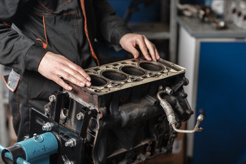 The mechanic disassemble block engine vehicle. Engine on a repair stand with piston and connecting rod of automotive technology. Interior of a car repair shop.