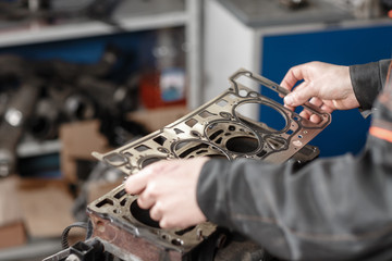 Sealing gasket in hand. The mechanic disassemble block engine vehicle. Engine on a repair stand...