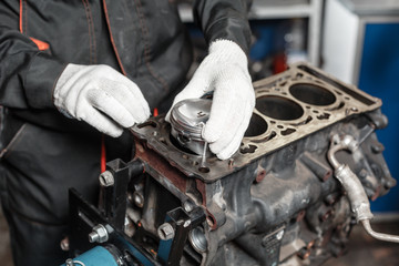 the mechanic installs a new piston. Disassemble engine block vehicle. Motor capital repair. Sixteen valves and four cylinder. Car service concept.