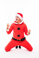 Happy young man in Santa Claus wear sliding on the knees isolated on white background