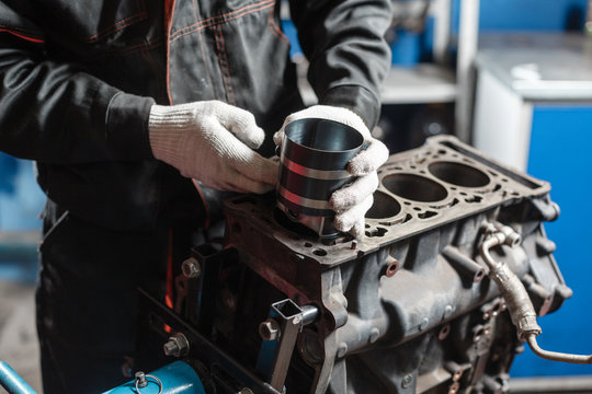 the mechanic installs a new piston. Disassemble engine block vehicle. Motor capital repair. Sixteen valves and four cylinder. Car service concept.