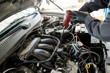 Asian car mechanic fixing a car in his auto repair shop