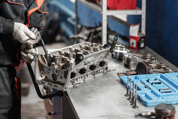 Naklejka premium the mechanic opened the locking valve mechanism. Disassemble engine block vehicle. Motor capital repair. Sixteen valves and four cylinder. Car service concept.