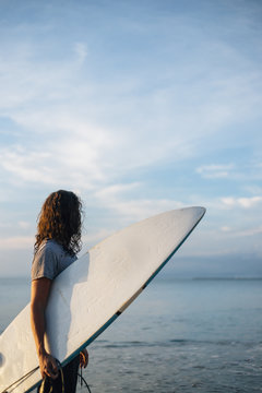 Surfer on beach in sunrise