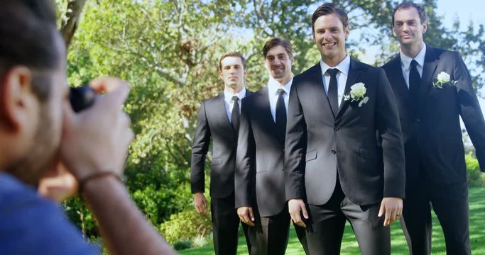 Photographer taking photo of groom and groomsmen  