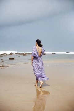 A beautiful woman walking along the beach on a dark day