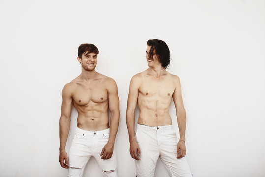 Two male models posing against white wall
