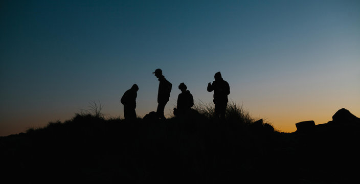 Silhouette of four men on top of sand dunes