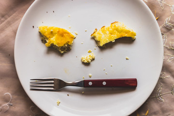 Fork and pieces of eggs on a plate in the form of a face
