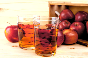 Apple juice and fresh apples in a wooden box.