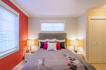 Modern bedroom interior with a red wall, designer pillows, and a floral duvet cover in a luxury house.