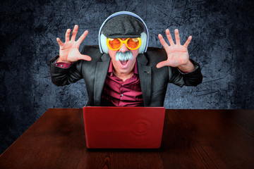 Alter Mann mit Kopfhörer und Schnäuzer hört Musik am Computer