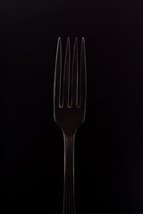 Steel fork on black background. Metal fork on dark background close up.