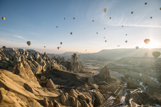 lot of colorful hot air balloons above rugged sandstone landscape of cappadocia at sunrise, turkey