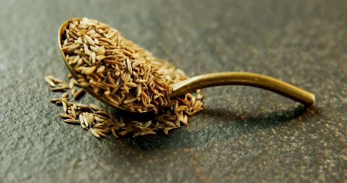 Cumin seeds in spoon on concrete background 