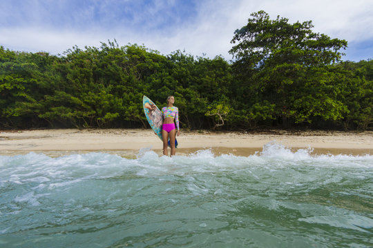 Female surfer standing at the baech