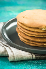 Homemade pancakes stack in pile on plate.
