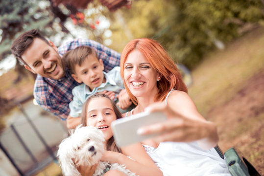 Smiling young family taking selfie in the park.