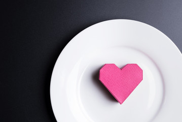 Box red heart shape in the white dish on black background with copy space.Valentine's Day, Day of love.
