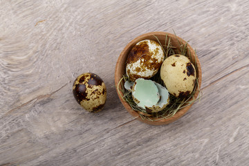 Quail eggs and eggshell on a wooden background.
