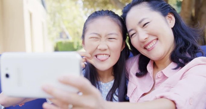 Daughter and mother taking selfie with mobile phone 